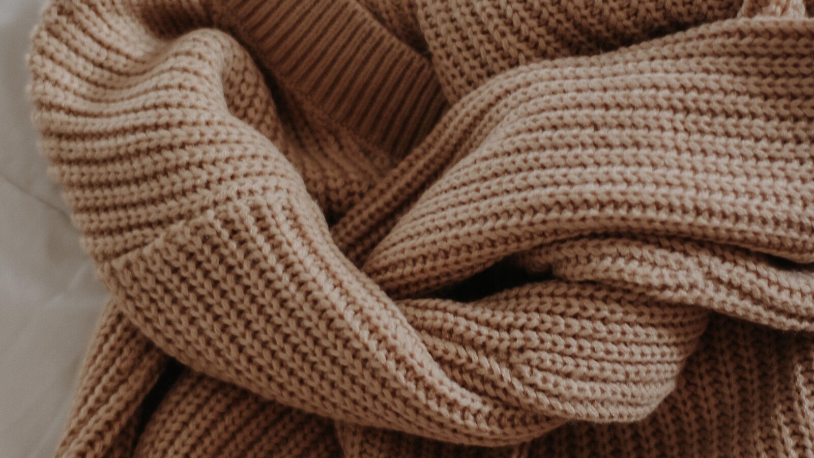 Folded neutral knitwear on an open shelf